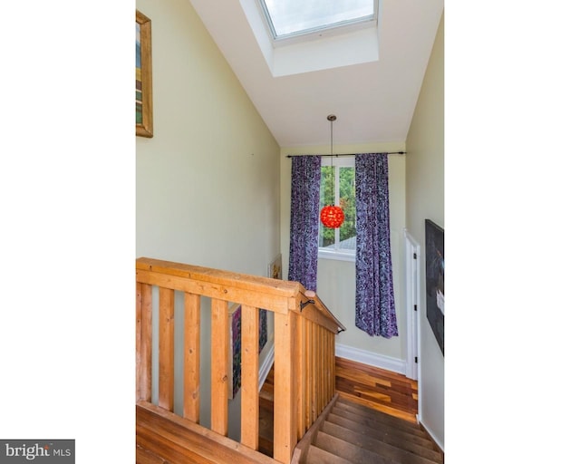 stairway featuring vaulted ceiling with skylight and dark hardwood / wood-style flooring