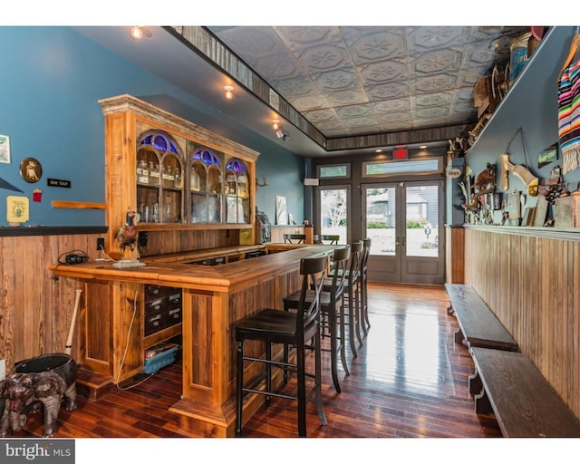 bar with french doors, wooden walls, and dark hardwood / wood-style floors