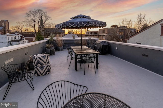 patio terrace at dusk featuring a balcony and area for grilling