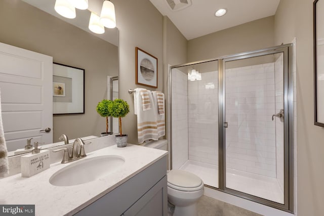 bathroom featuring a shower with shower door, toilet, tile floors, and vanity with extensive cabinet space