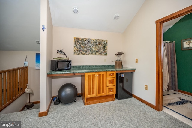 carpeted office space featuring vaulted ceiling