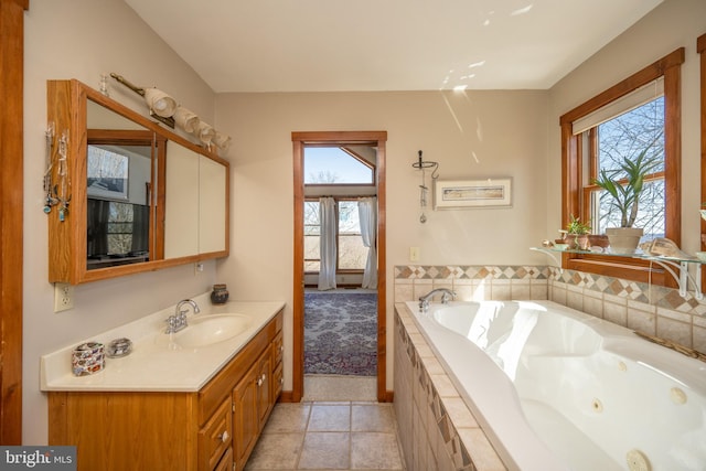 bathroom featuring tile patterned floors, vanity, a relaxing tiled tub, and a healthy amount of sunlight