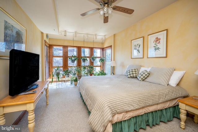 carpeted bedroom featuring rail lighting and ceiling fan