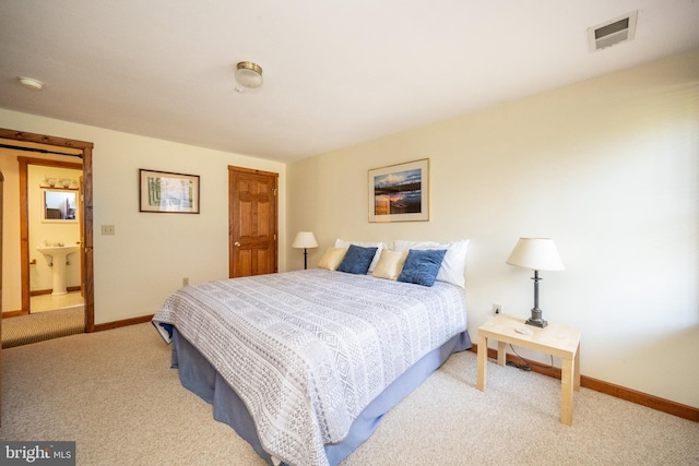 carpeted bedroom with ensuite bathroom and sink