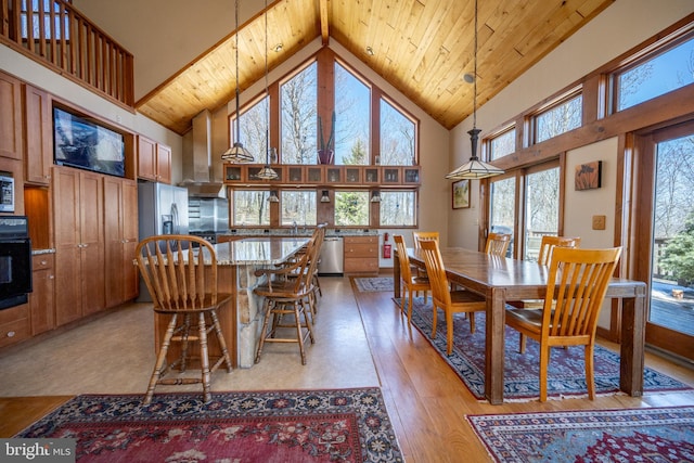 dining space with plenty of natural light, light hardwood / wood-style floors, and high vaulted ceiling