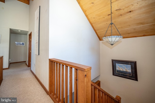 hall with light colored carpet, lofted ceiling, and wood ceiling