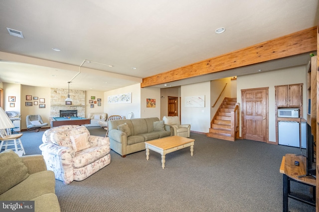 carpeted living room featuring beam ceiling and a fireplace