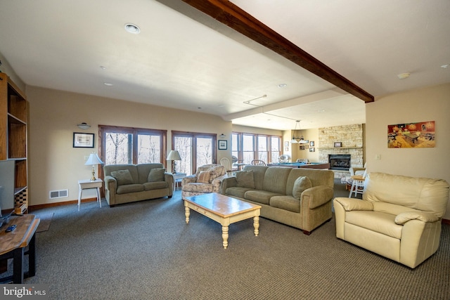 carpeted living room with beamed ceiling, a notable chandelier, a healthy amount of sunlight, and a fireplace