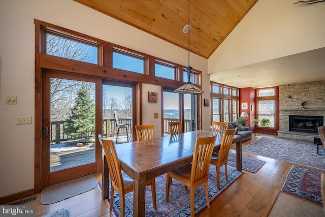 dining area with a fireplace, hardwood / wood-style flooring, high vaulted ceiling, and wood ceiling