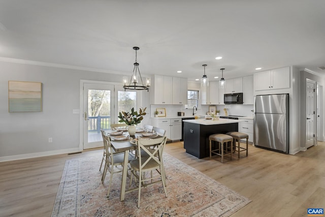 dining room with a notable chandelier, crown molding, light hardwood / wood-style floors, and sink