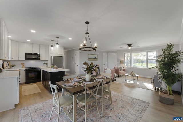 dining room with ornamental molding, light hardwood / wood-style floors, and ceiling fan with notable chandelier