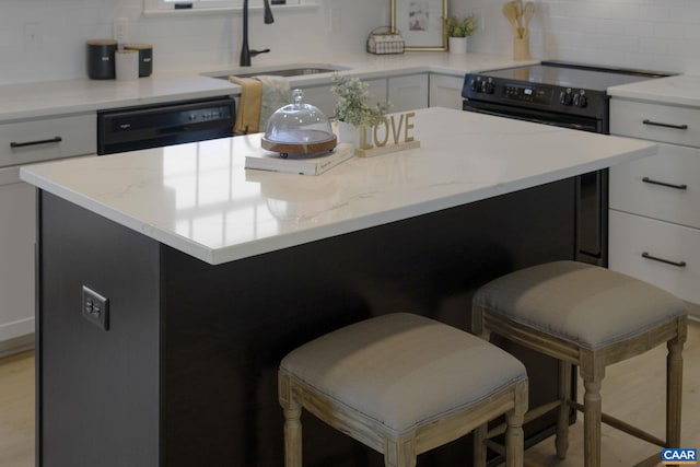 kitchen featuring a kitchen island, sink, backsplash, and white cabinetry