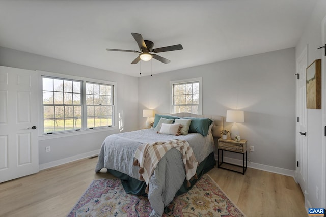 bedroom with ceiling fan, multiple windows, and light hardwood / wood-style flooring