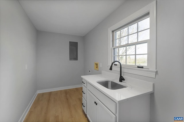 kitchen featuring light stone counters, white cabinetry, sink, and light wood-type flooring