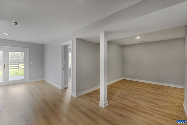 basement featuring light hardwood / wood-style flooring and french doors