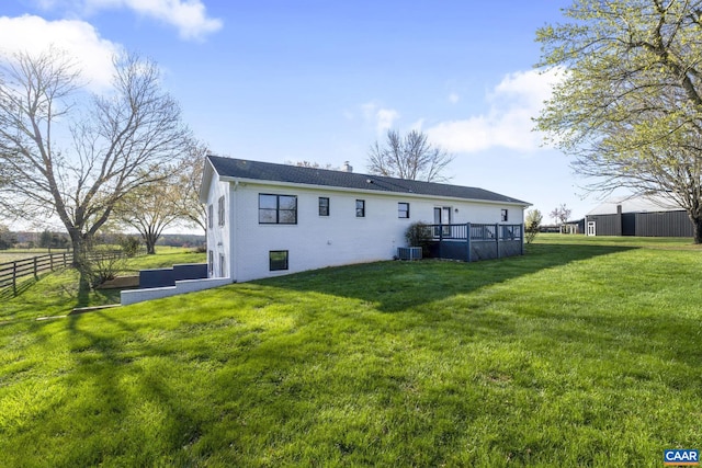 rear view of house featuring central AC unit and a lawn