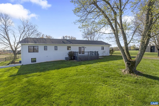 rear view of property featuring a deck, central air condition unit, and a lawn