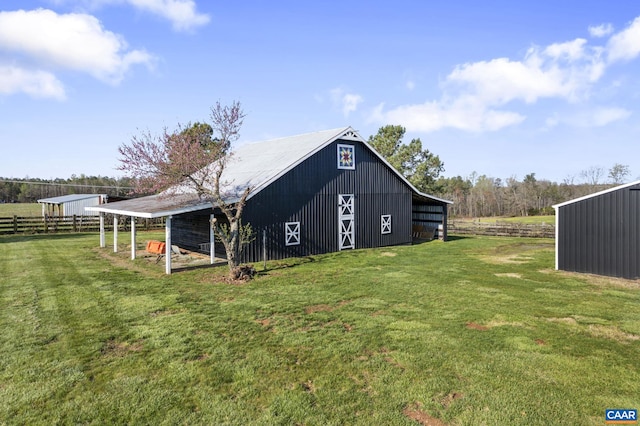 back of house featuring an outdoor structure, a yard, and a rural view