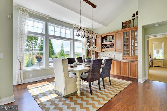 dining room featuring an inviting chandelier, brick wall, high vaulted ceiling, and light hardwood / wood-style floors