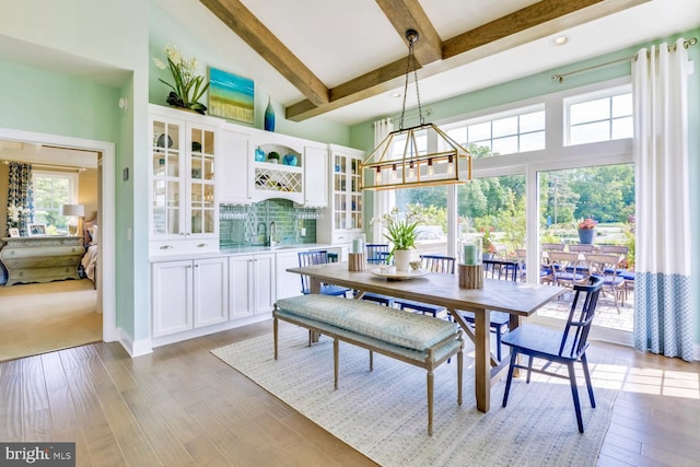 dining room with a notable chandelier, beamed ceiling, and light hardwood / wood-style flooring