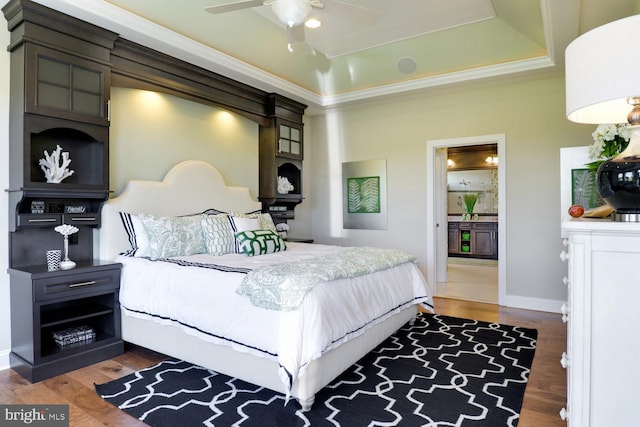 bedroom featuring ceiling fan, a raised ceiling, and dark wood-type flooring