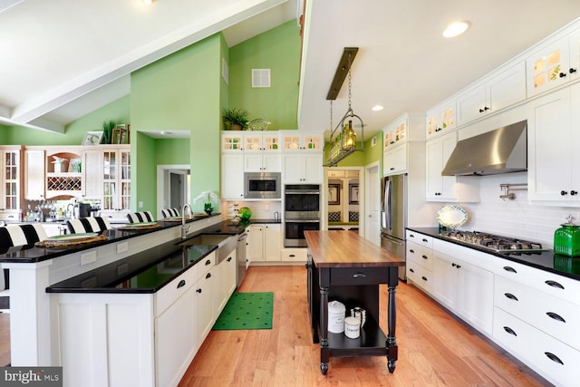 kitchen featuring light hardwood / wood-style floors, a kitchen bar, stainless steel appliances, a center island, and wall chimney range hood