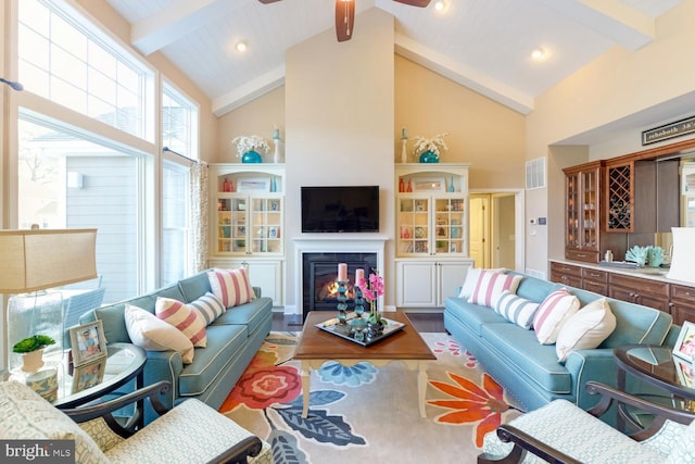 living room with ceiling fan, high vaulted ceiling, and beamed ceiling