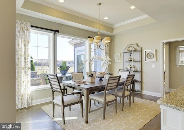 dining area featuring a chandelier, a tray ceiling, and wood-type flooring