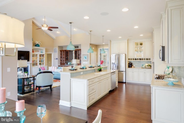 kitchen with light stone countertops, backsplash, ceiling fan, dark wood-type flooring, and appliances with stainless steel finishes