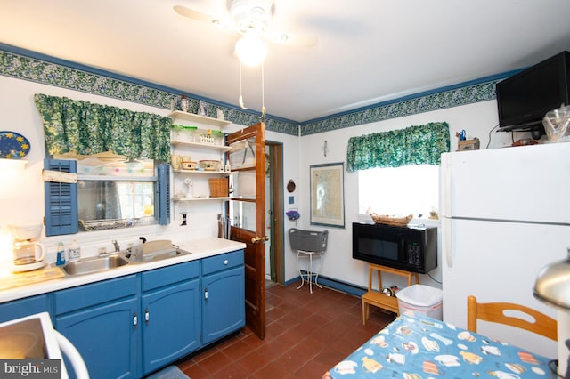 kitchen with blue cabinetry, ceiling fan, white fridge, and sink