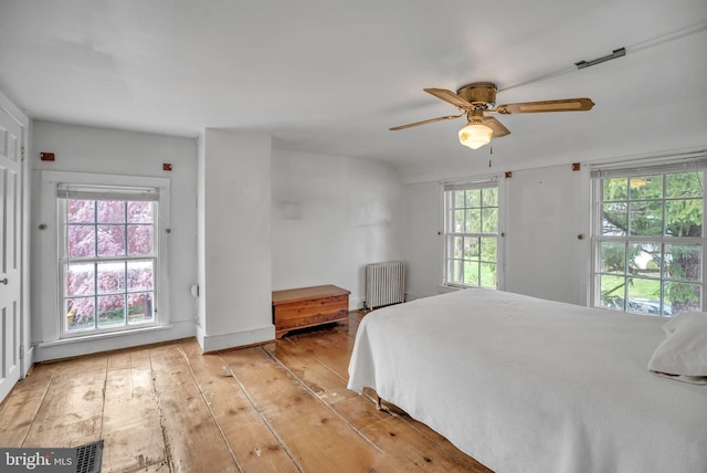 bedroom with radiator heating unit, light hardwood / wood-style floors, and ceiling fan