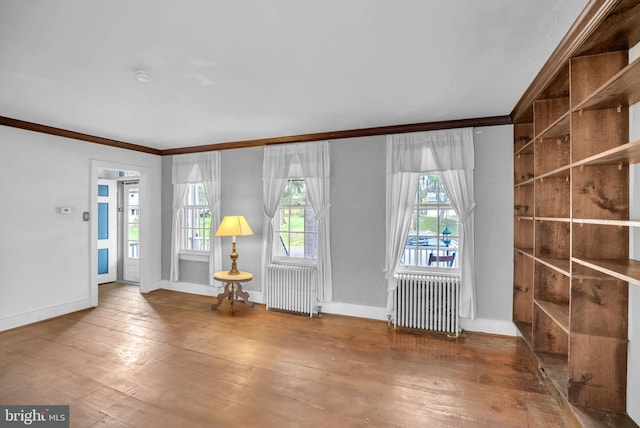 foyer featuring radiator heating unit, wood-type flooring, and ornamental molding