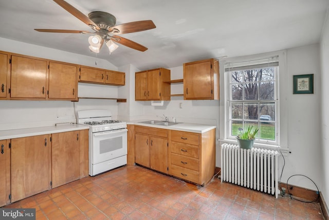 kitchen with ceiling fan, white gas stove, radiator heating unit, sink, and vaulted ceiling