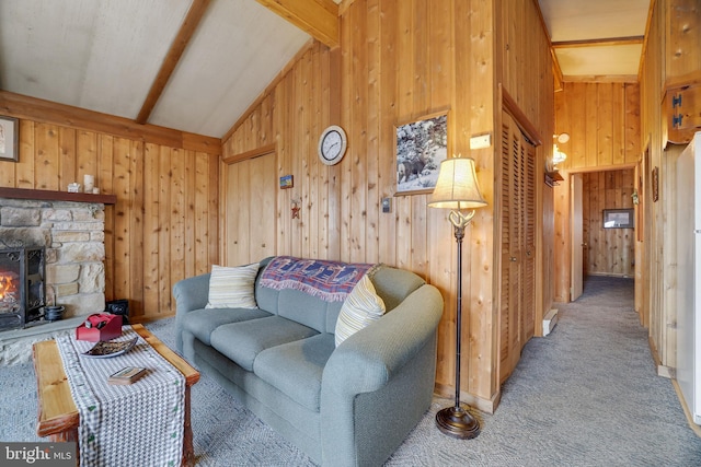 carpeted living room featuring vaulted ceiling with beams, wooden walls, and a fireplace