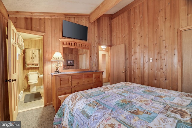 carpeted bedroom featuring ensuite bath, wood walls, and lofted ceiling with beams