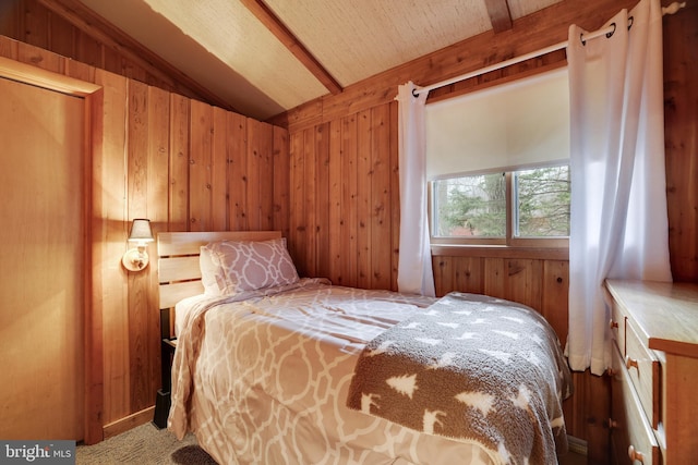 carpeted bedroom with vaulted ceiling and wooden walls