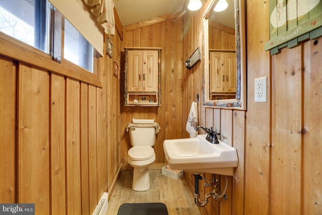 bathroom featuring hardwood / wood-style flooring, wood walls, vaulted ceiling, and toilet