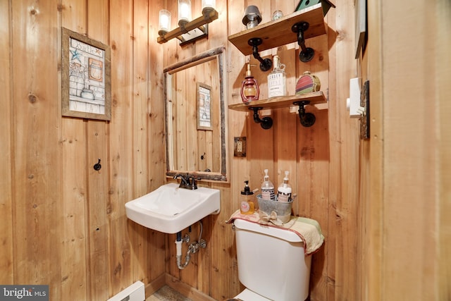 bathroom featuring wood walls, toilet, and sink