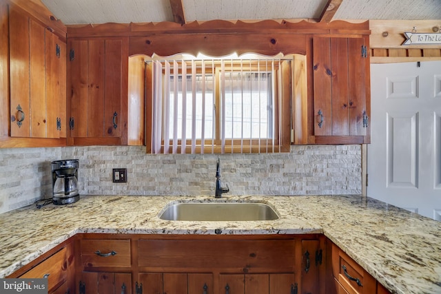 kitchen with tasteful backsplash, beam ceiling, sink, and light stone counters