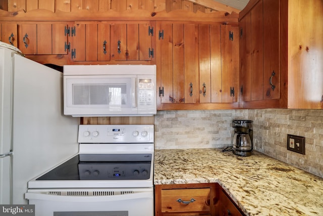 kitchen with backsplash, white appliances, and light stone counters