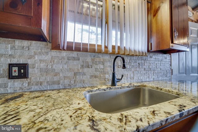 kitchen with sink, backsplash, and light stone countertops