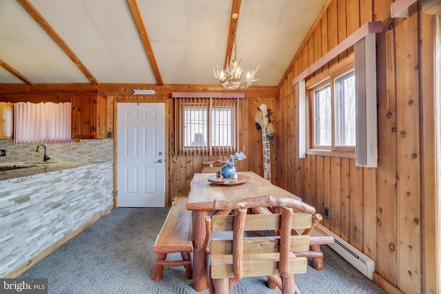 carpeted dining room featuring lofted ceiling with beams, a notable chandelier, a healthy amount of sunlight, and wooden walls