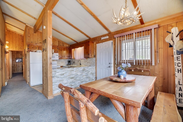 carpeted dining space featuring sink, vaulted ceiling with beams, and a chandelier