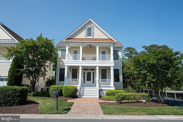 neoclassical / greek revival house with covered porch, ceiling fan, and a balcony