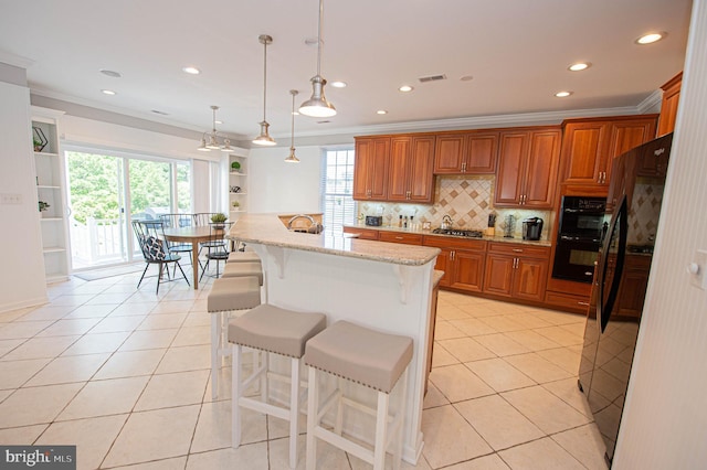 kitchen featuring light stone counters, a breakfast bar, black appliances, hanging light fixtures, and light tile patterned flooring