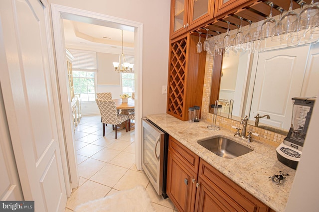 kitchen featuring light stone countertops, beverage cooler, sink, pendant lighting, and light tile patterned floors