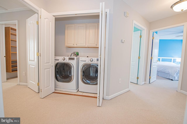 washroom featuring washer and clothes dryer, cabinets, and light carpet