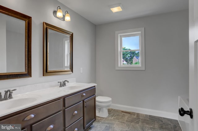 bathroom with tile flooring, double sink vanity, and toilet