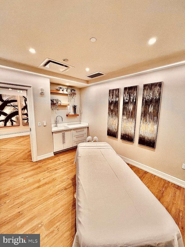 bedroom featuring light hardwood / wood-style flooring, sink, and a textured ceiling