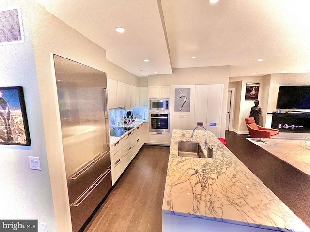 kitchen featuring light stone countertops, white cabinetry, sink, stainless steel appliances, and dark hardwood / wood-style flooring